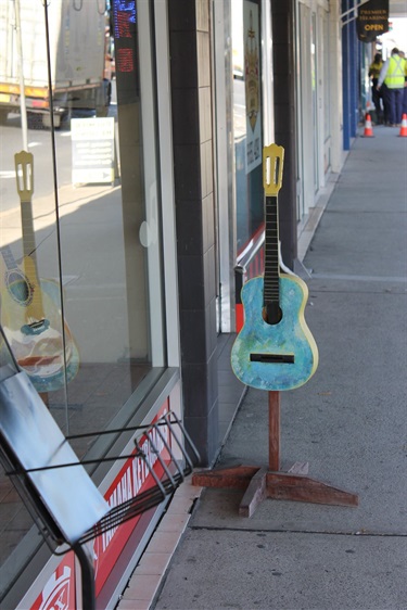 Guitar being used as a sign on footpath