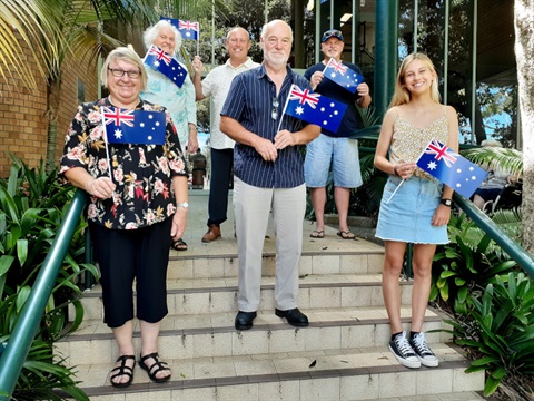 Australia Award nominees pictured on the steps of the Coffs Harbour City Council building holding Australian flags