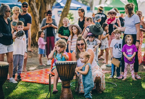 A crowd of people looking happy outside at a festival with drums